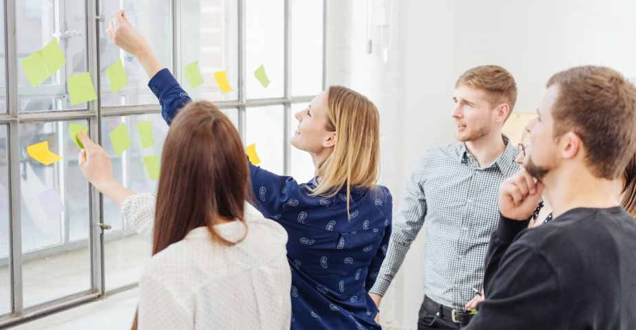 Kuvassa kaksi naista ja kaksi miestä post-it -lappujen parissa työskentelemässä